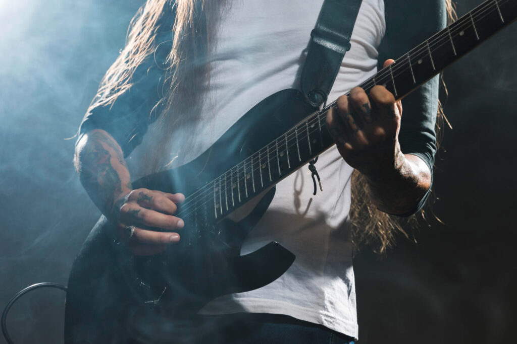 Guitarrista tocando em show de rock; Dia Mundial do Rock é em 13 de julho: veja músicas para usar como repertório no vestibular