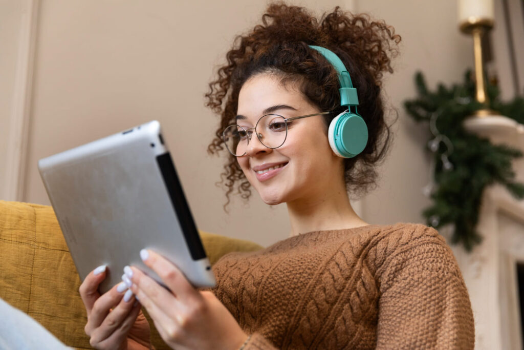 Estudante com fone de ouvido segurando um tablet; saiba se é possível aprender ingles com IA