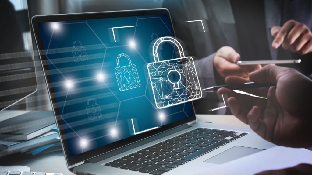Ícone de cadeado projetado sobre a tela de um computador. A imagem simboliza a prática de Segurança da Informação.