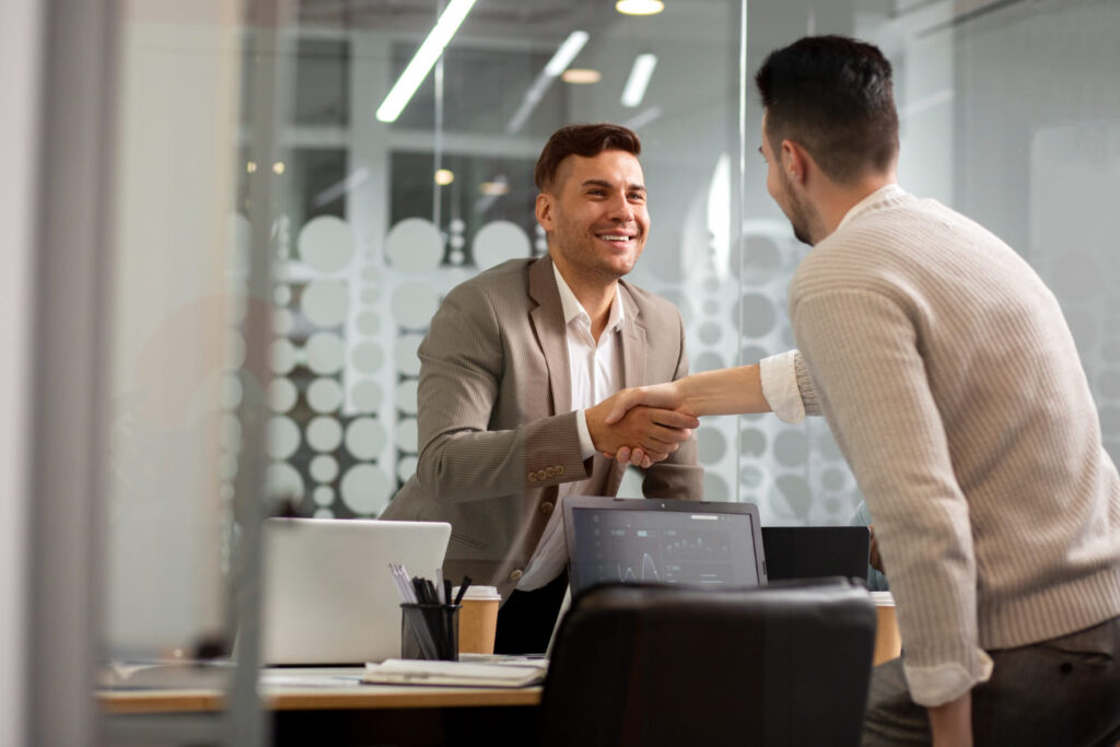 Funcionário de empresa cumprimentando cliente de forma amigável e feliz; Dia do Cliente: veja frases e mensagens para enviar