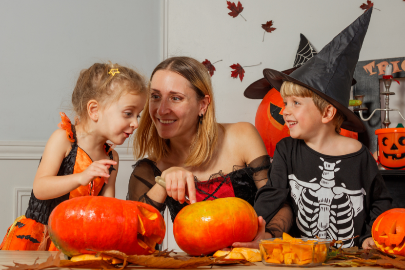 mãe e dois filhos esculpindo abóboras como atividade de halloween 