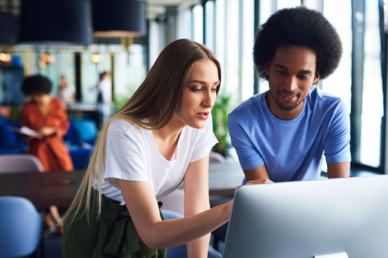 Profissionais colaborando em um ambiente moderno de escritório, discutindo sobre tecnologia e sistemas, refletindo a dinâmica de aprendizado e desenvolvimento no curso de Análise e Desenvolvimento de Sistemas.
