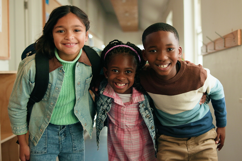três crianças abraçadas e felizes no dia da consciência negra