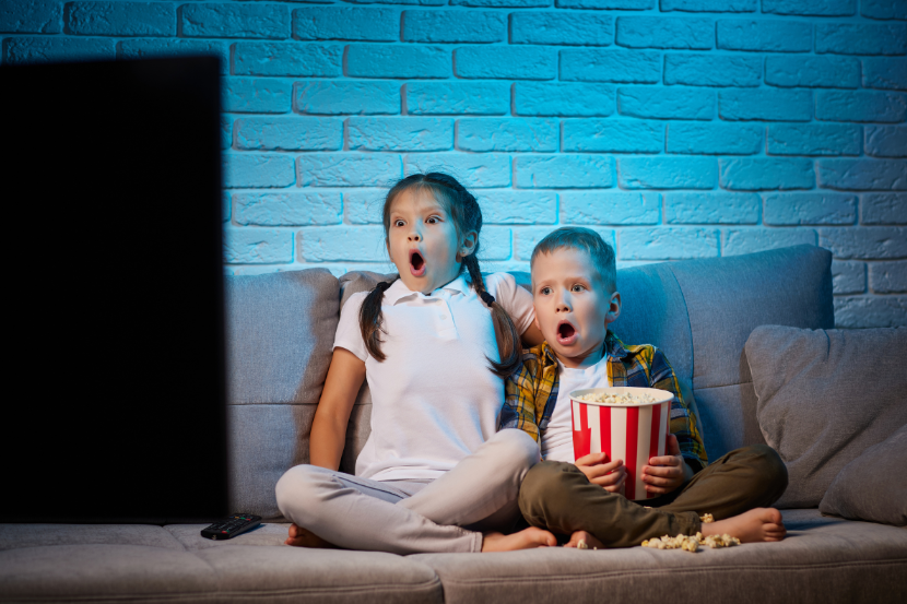 duas crianças assustadas assistindo stranger things com pipoca na mão