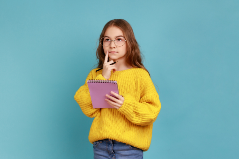 menina com expressão de dúvida e caderno na mão