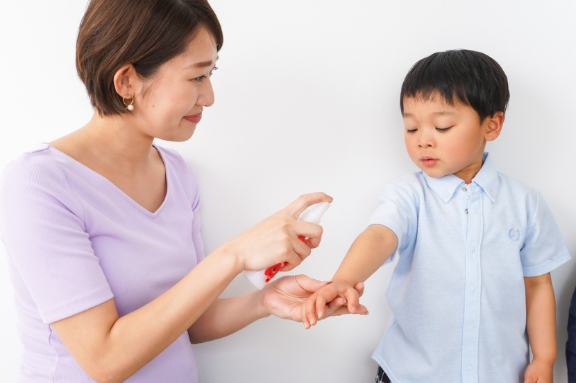 mãe passando repelente no filho