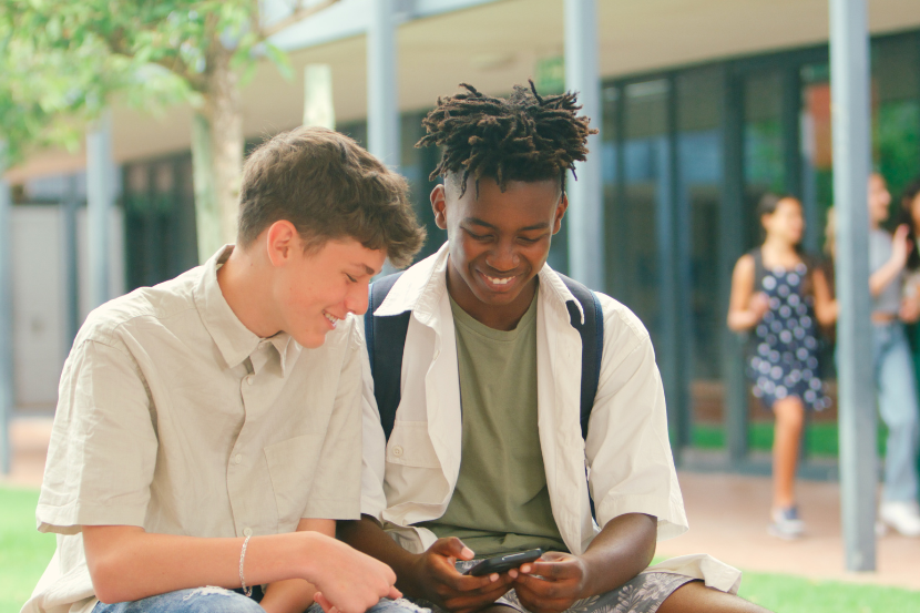 dois adolescentes usando celular na escola 