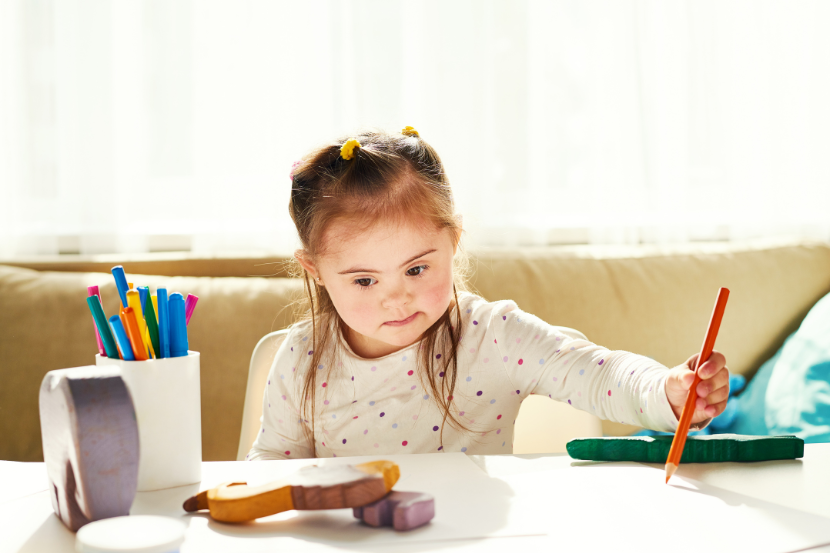criança com síndrome de down pintando com lápis de cor