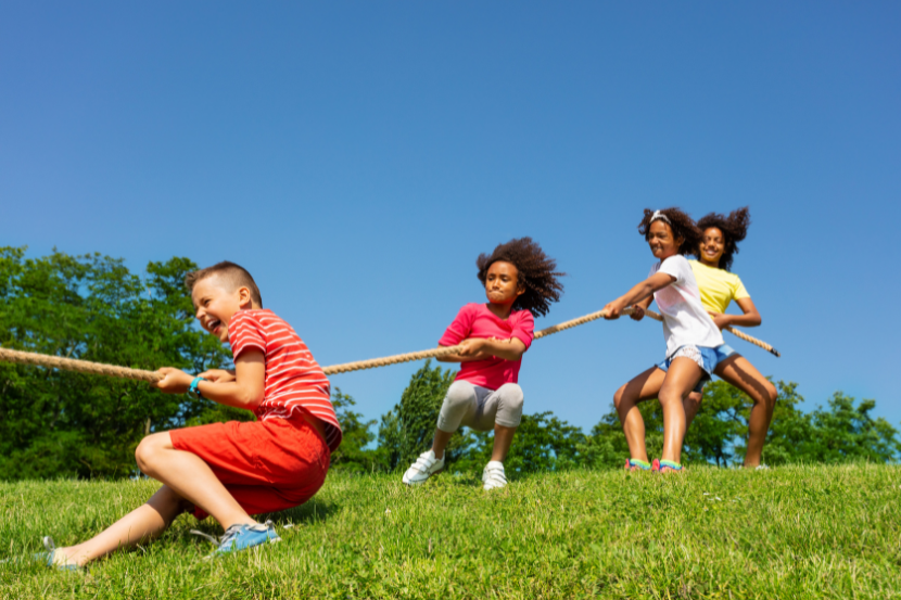 crianças brincando de cabo de guerra em acampamento de férias