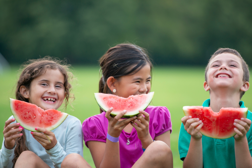 crianças felizes comendo melancia
