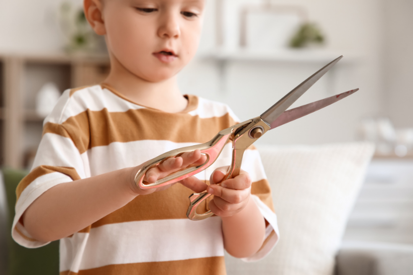 criança em risco de acidente doméstico segurando tesoura grande 