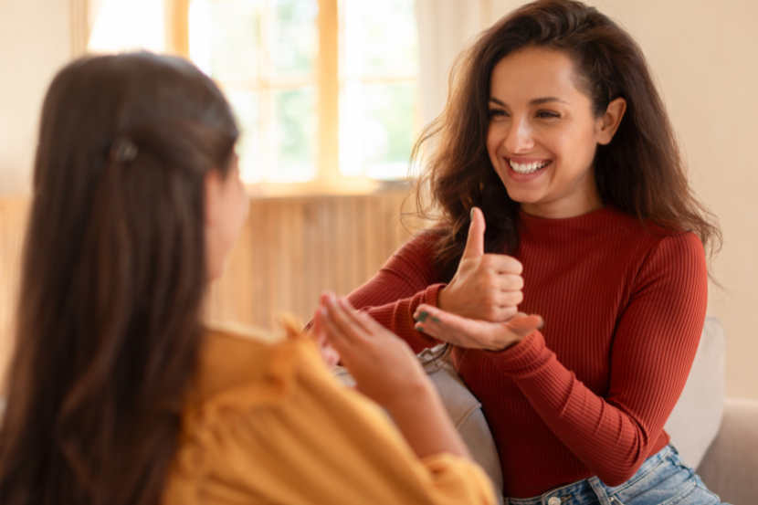 professora ensinando Libras a uma aluna representando o Dia Internacional da Língua Materna