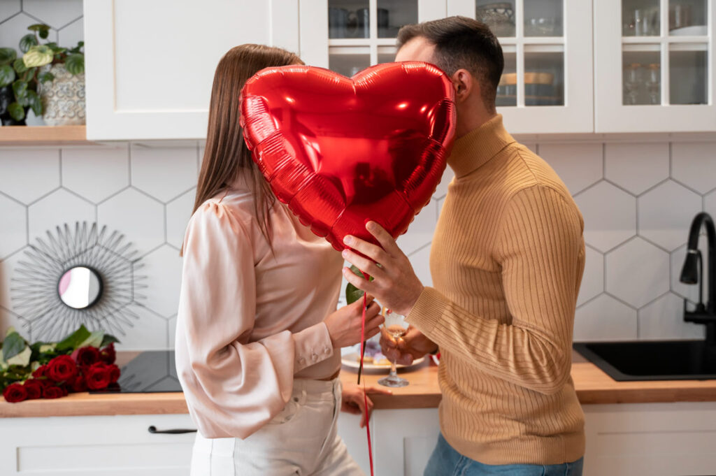 Um casal segurando um balão em formato de coração, um de frente para o outro; Valentine's day: o que significa e por que é comemorado em 14 de fevereiro