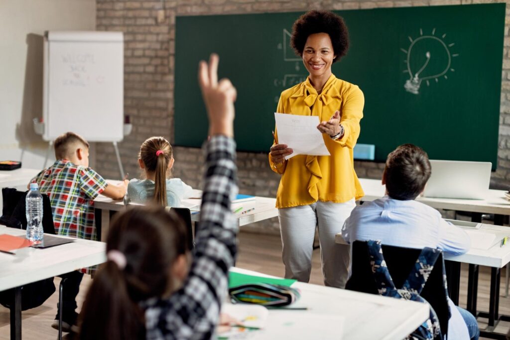 Professora em sala de aula com alunos, representando pedagogia ou normal superior e a formação para dar aula na educação básica.