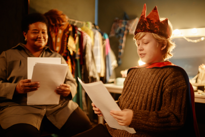 aluno lendo roteiro de peça de teatro com professora