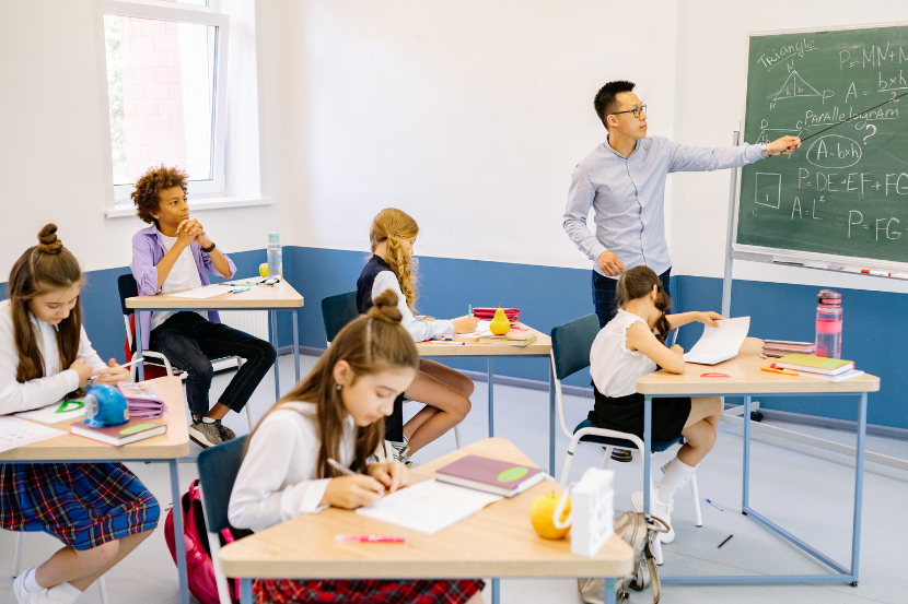 sala de aula com alunos e professor ensinando conteúdo na lousa
