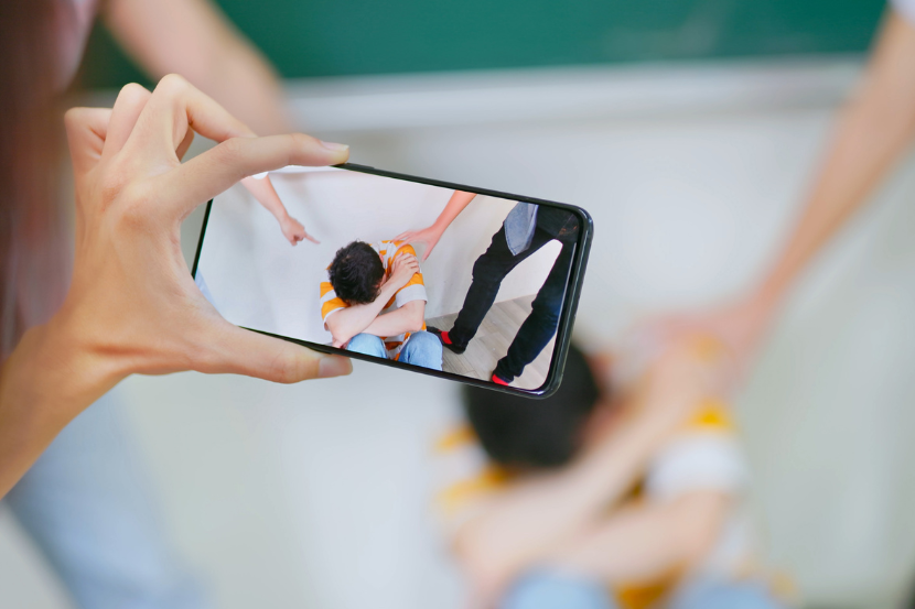 prática de cyberbullying na escola com pessoa filmando situação de agressão