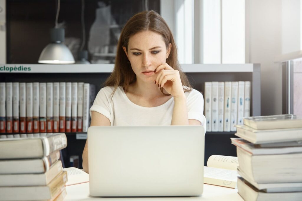Jovem estudante em frente ao computador pesquisando onde ver o edital da Fuvest 2027