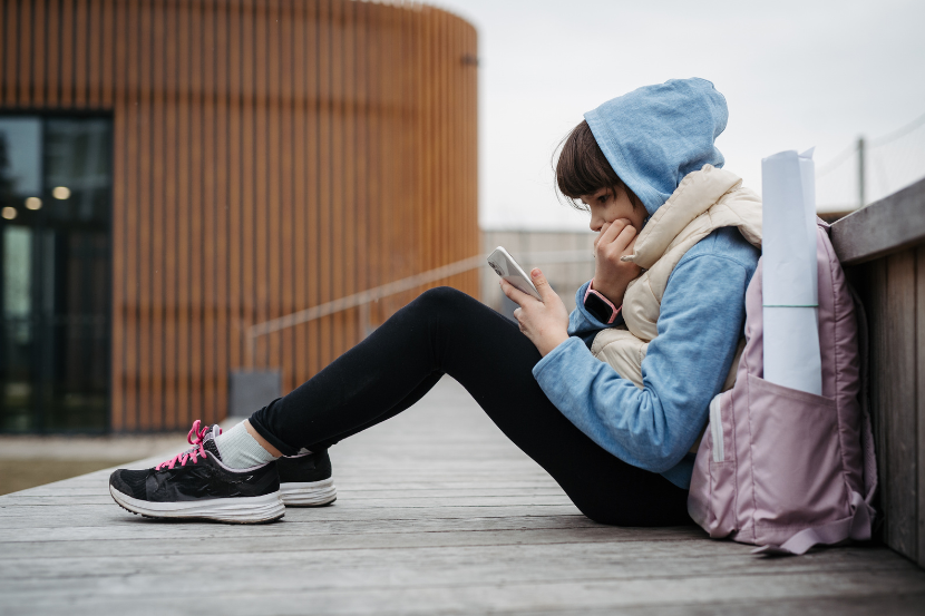 aluna olhando o celular chocada com o que está vendo na tela 