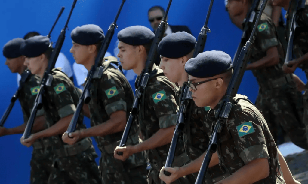 Jovens brasileiros servindo ao Exército e marchando; entenda se fazer faculdade dispensa do serviço militar