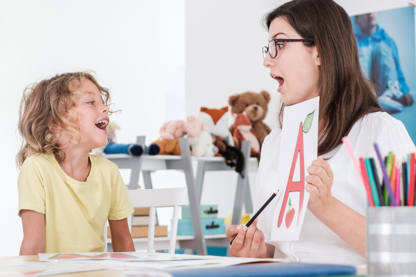 profissional trabalhando com criança que troca letras escrevendo 