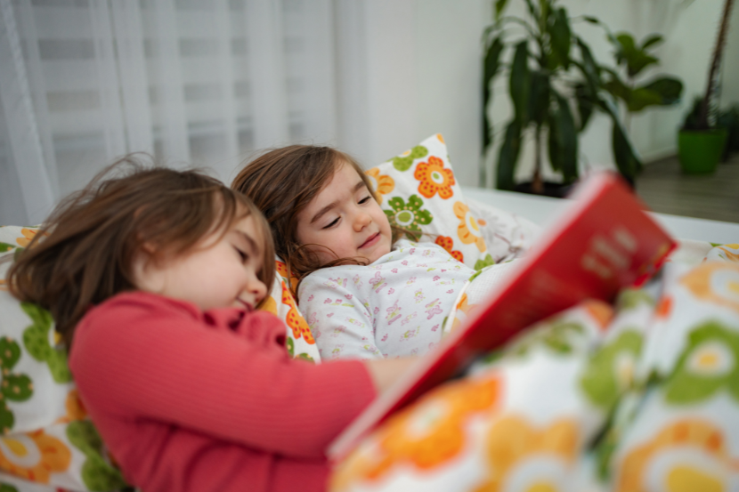 duas meninas deitadas lendo livro infantil antes de dormir