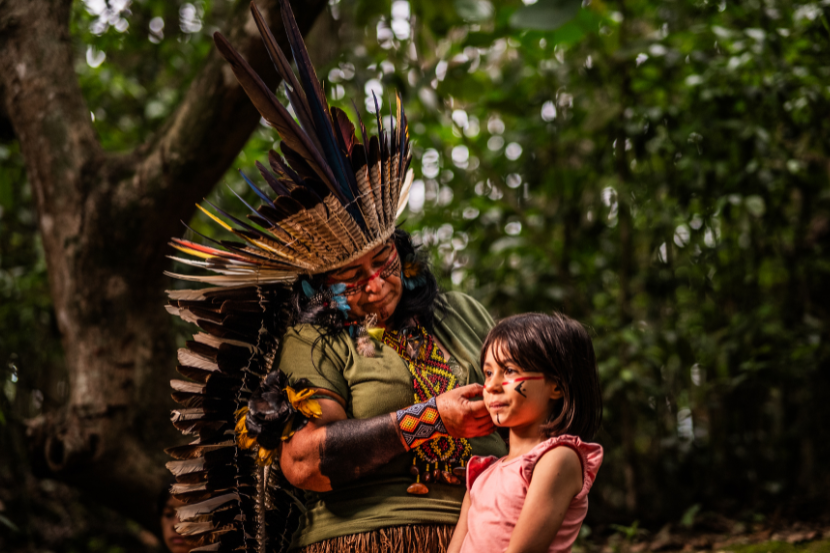 índia pintando o rosto de pequena menina  indígena 