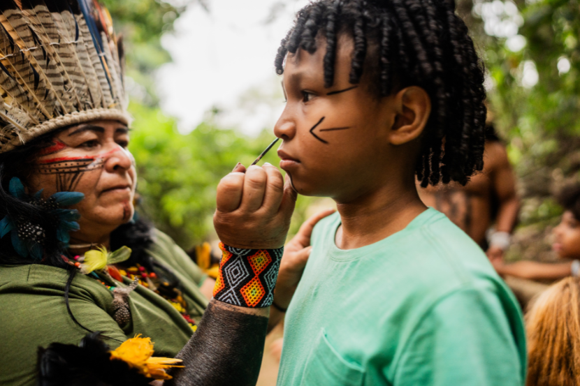 índia pintando rosto de menino para ensinar às crianças sobre os povos indígenas