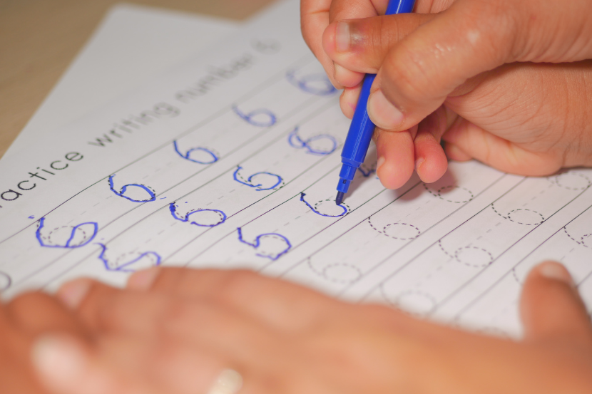 adulto segurando na mão da criança em atividades pontilhadas de caligrafia