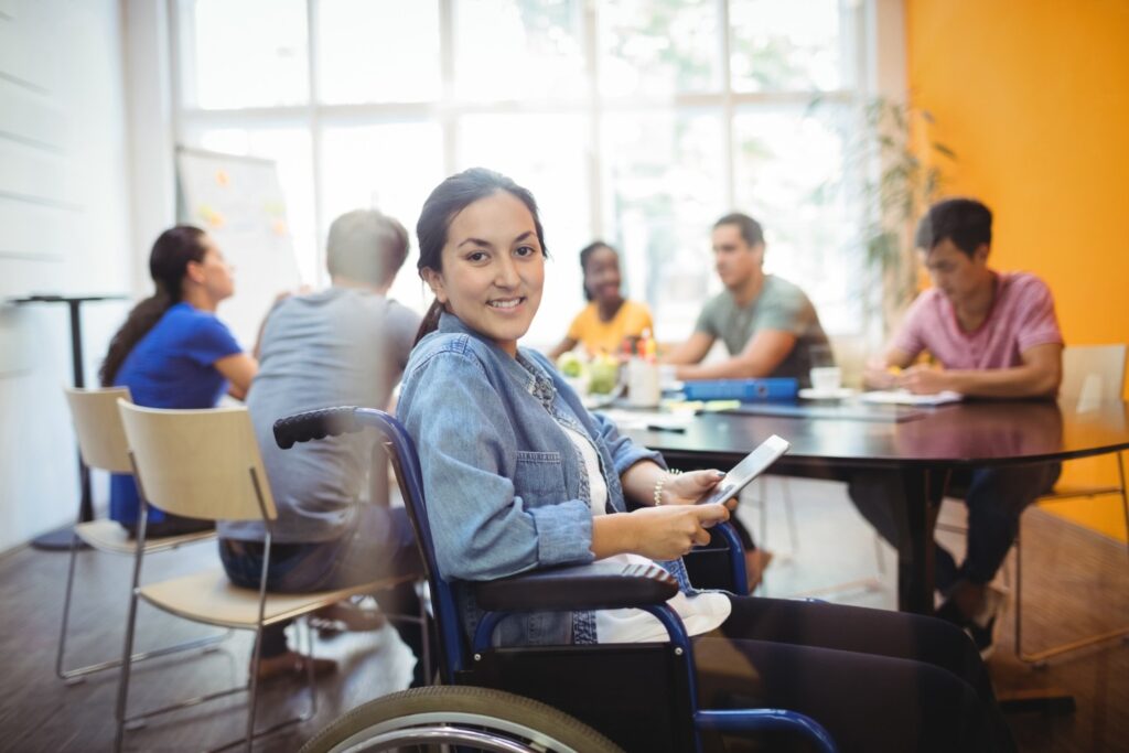 Estudante em cadeira de rodas em ambiente universitário, representando como escolher faculdade de Serviço Social com foco em acessibilidade, estrutura e qualidade do curso.