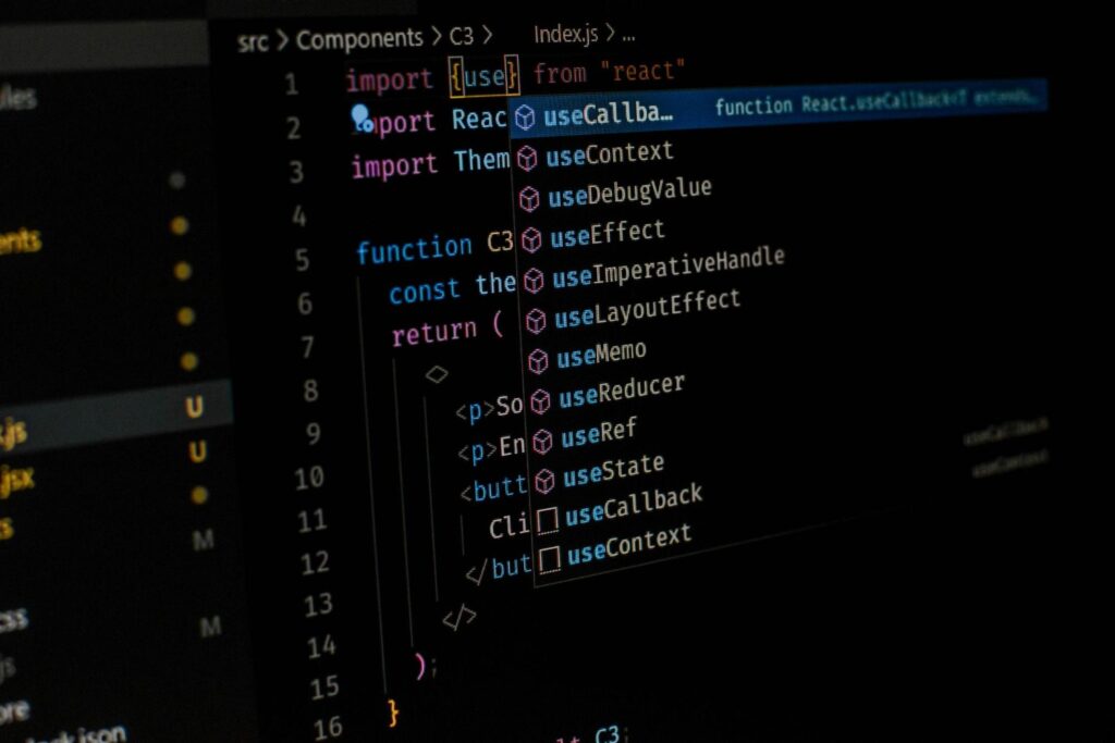 Tela de computador mostrando código de programação em JavaScript com sugestões de funções do React em um editor de código, em referência a Ciência da Computação.
