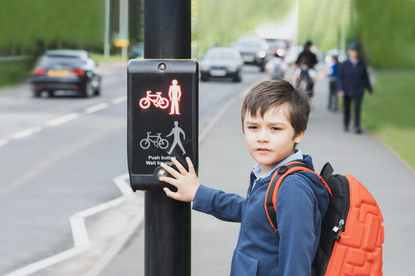 criança apertando botão para atravessar a rua no dia mundial do trânsito