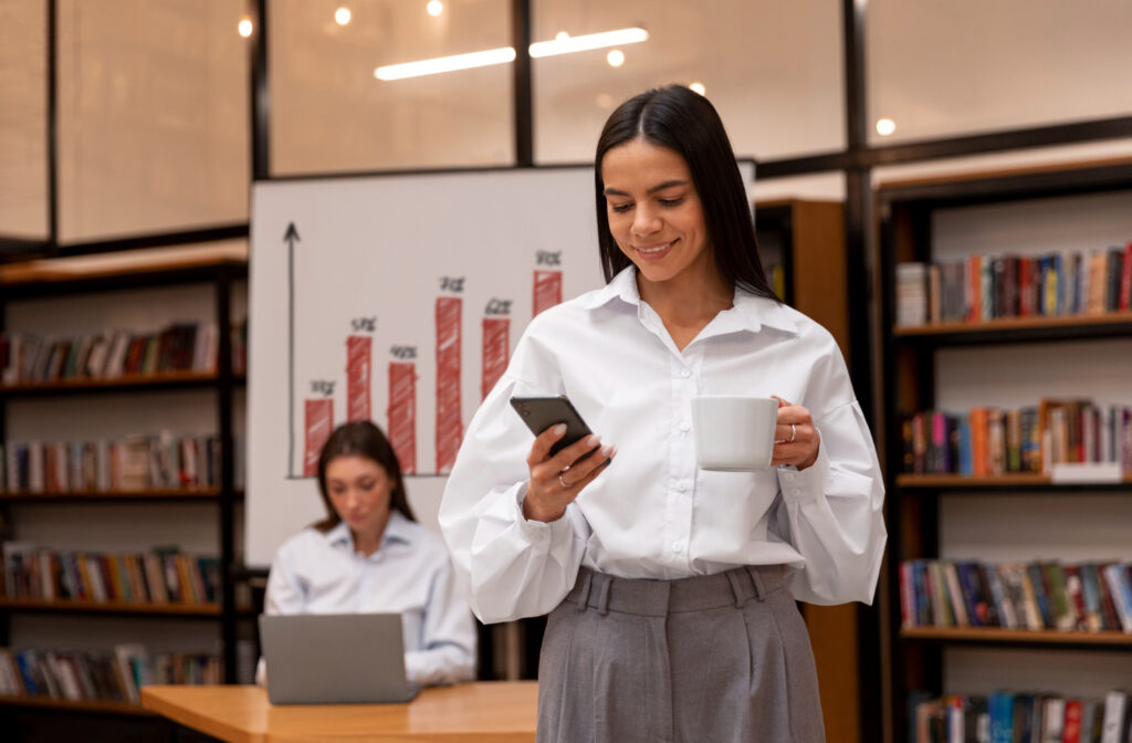 Mulher conferindo celular em escritório, simbolizando planejamento e análise de resultados em gestão comercial; conceito de gestão comercial vale a pena.