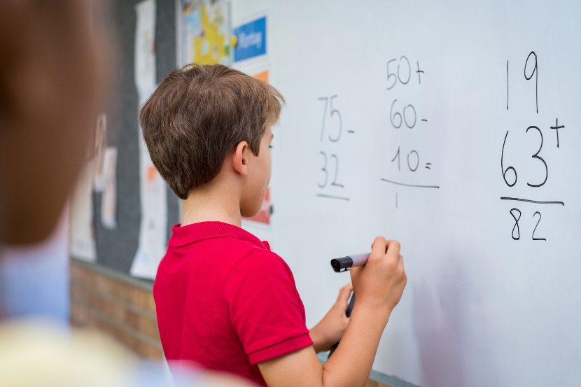 criança fazendo contas de matemática na lousa