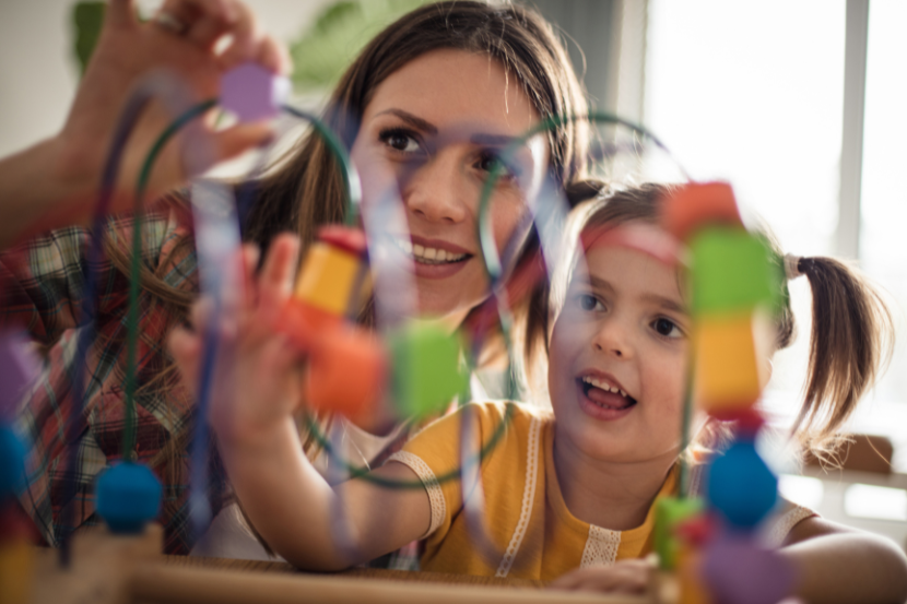 professora ensinando criança a brincar com brinquedo de blocos