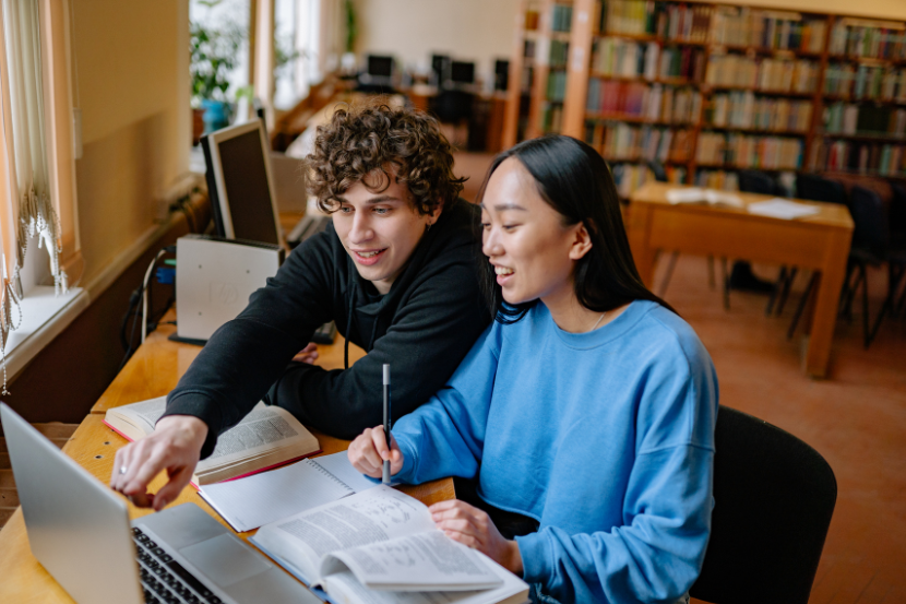 dois estudantes adolescentes estudando juntos com materiais de estudo e computador