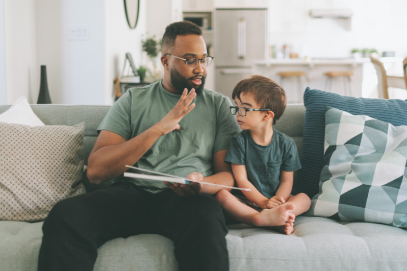 paia lendo um livro em libras para filho em casa no dia nacional do surdo