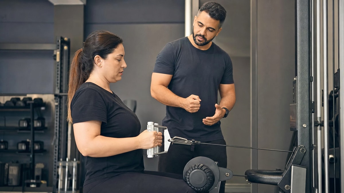 Adaptação inicial Pessoa iniciante aprendendo um movimento de musculação com orientação profissional
