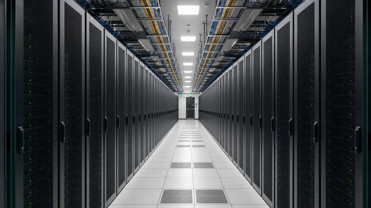 Infraestrutura de servidores garantindo alta disponibilidade Fileira organizada de racks de servidores em data center moderno com luzes de operação ativas.