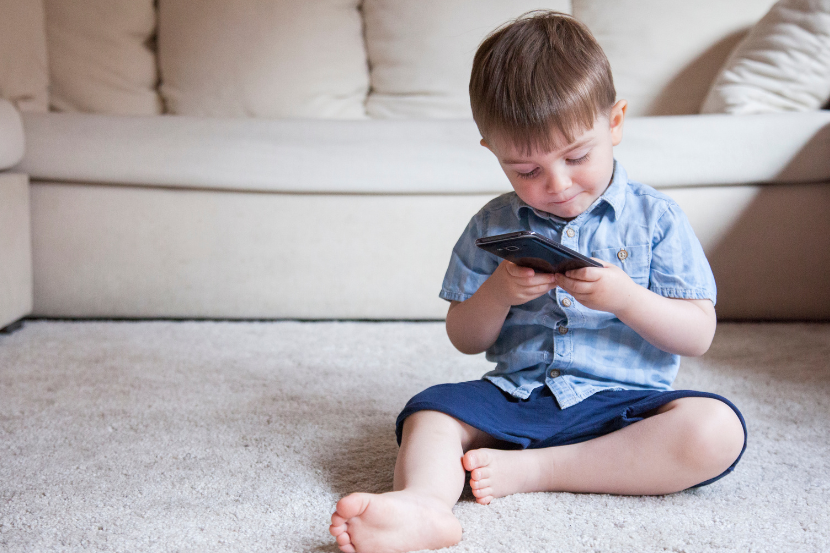 criança menor de 3 anos mexendo no celular sozinho na sala de casa
